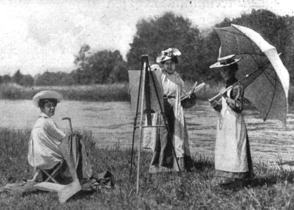 Sogenannte "Malweiber", weibliche Malerinnen um 1900. Eine Malerin sitzt auf einem Klappstuhl, eine weitere malt an der Staffelei und ein Mädchen hält einen großen Sonnenschirm.