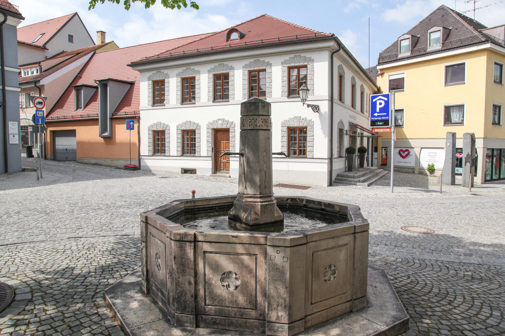Blick auf kopfsteingepflasterte Kreuzung in der Altstadt, restaurierte Altstadthäuser im Hintergrund, plätschernder Roßmarktbrunnen im Vordergrund.