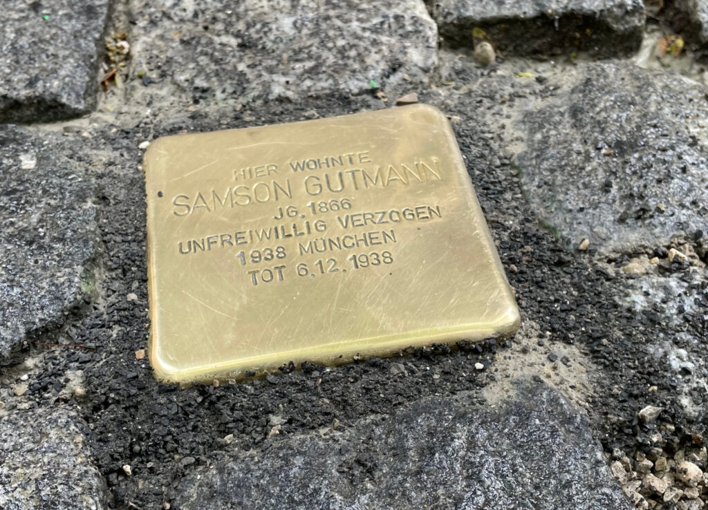 Das Bild zeigt einen frisch in den Boden eingelassenen Stolperstein, hier für Samson Gutmann in Dachau